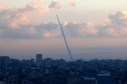 Members of the Israeli security forces take cover on the side of a street in Ashkelon as sirens wail while barrages of rockets are fired from the Gaza Strip 