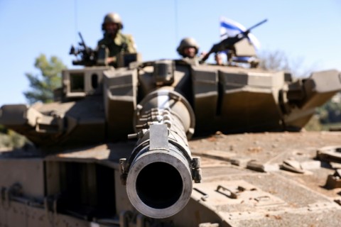 An Israeli tank crew mans a position on the Lebanese border as the army trades fire with Iran-backed militant group Hezbollah