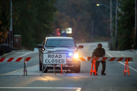 A law enforcement official blocks the road to Schemengees Bar where the shooting took place in Lewiston, Maine