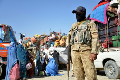 An Afghan police personnel stands guard as refugees arrive at the Afghanistan-Pakistan border in Spin Boldak 