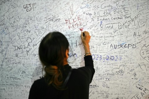 A woman writes a message for team India on a fan wish wall in Ahmedabad airport 