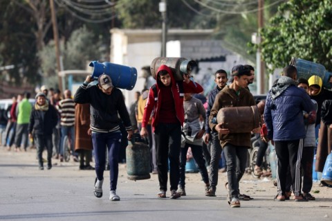 Palestinians in Rafah, the southern Gaza Strip, carry empty canisters to be filled with cooking gas from a shipment that entered as increased aid flows under the hostage release deal