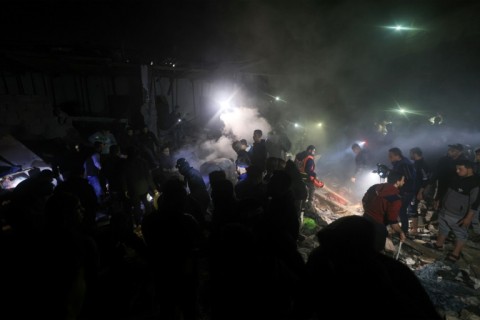 Palestinians check a half destroyed building in Rafah