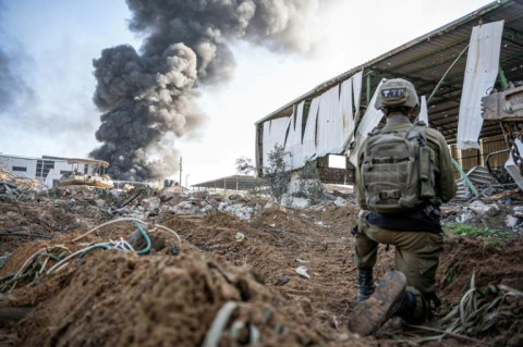 This handout picture released by the Israeli army on December 19, 2023 shows a soldier operating as smoke billows in the Gaza Strip