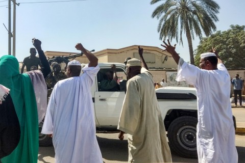 People displaced by the conflict in Sudan cheer as a Sudanese army truck driving by in the city of Gedaref