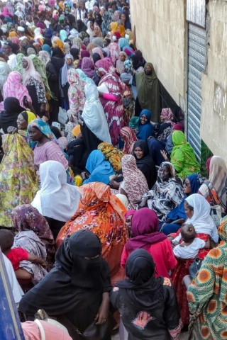 People from Sudan's Khartoum and Al-Jazira states queue to receive aid from a charity organisation in Gedaref