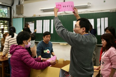 An official of a polling station holds up a ballot slip, as vote counting for the presidential elections commences, at a high school in New Taipei City on January 13, 2024. Vote counting got under way 