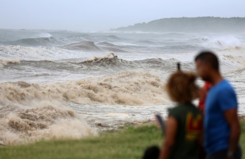 Members of the public take photos at the seafront ahead of the arrival of cyclone Belal