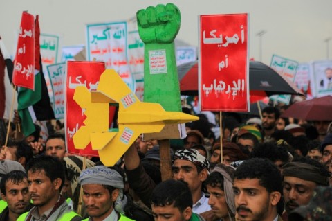 Protesters lift a mock fist and fighter plane, and placards in Arabic reading 'America is the mother of terrorism,' during an anti-Israel and anti-US rally in the Huthi-controlled capital Sanaa