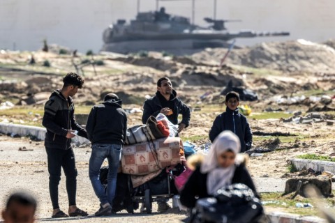 An Israeli battle tank guards a position as displaced Palestinians flee from Khan Yunis