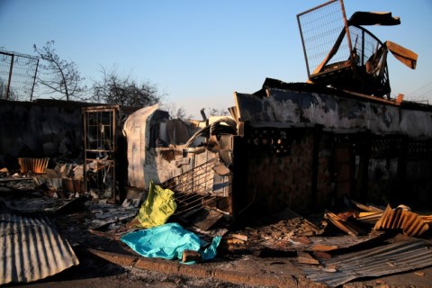 A covered body is seen next to a burned house after a fire consumed a hillside in Viña del Mar, Chile on February 3, 2024