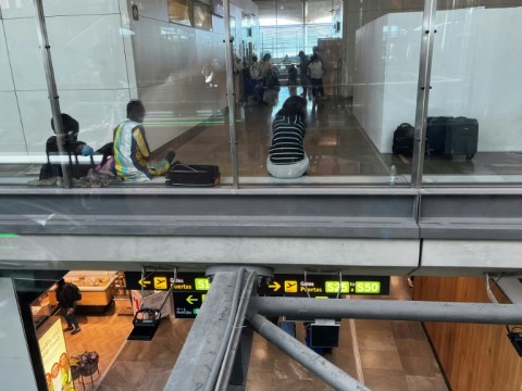 Migrants sit in the transit area of Madrid airport, which is struggling to cope with an influx of asylum seekers