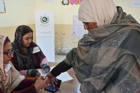 A polling officer marks the finger of a woman after she cast her ballot at a polling station in Islamabad 