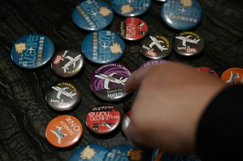 Jiang Hui, whose mother was on board flight MH370, shows buttons commemorating the missing flight