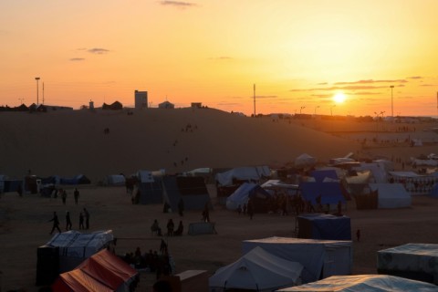 The sun sets behind a camp for displaced Palestinians in Rafah, in the southern Gaza Strip, on the eve of Ramadan