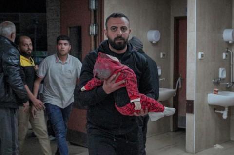 A Palestinian man carries an infant pulled out of the rubble of a house following Israeli bombardment, at the Al-Aqsa Martyrs Hospital in Deir Al-Balah in the central Gaza Strip on March 12, 2024