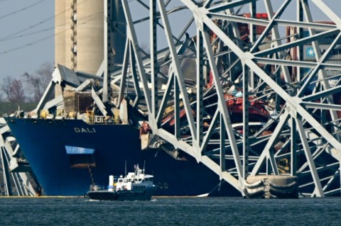 The collapsed Francis Scott Key Bridge lies on top of the container ship Dali in Baltimore, Maryland, on March 29, 2024, as clean-up work begins