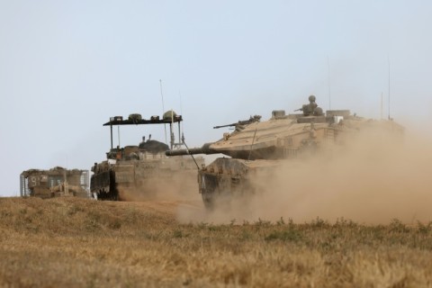 Israeli military vehicles roll near the border with the Gaza Strip