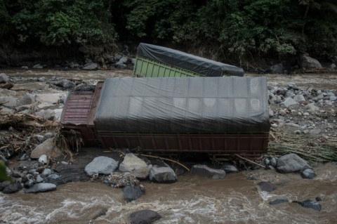 In the flood-hit district of Tanah Datar, the flooding left roads caked in mud, trucks sticking out of a nearby river and mosques smashed by logs and metal sheets