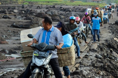 People drive their motorcycles over a makeshift pathway made from wodden slabs in western Indonesia