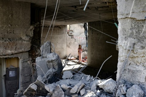 Children stand near a crater caused by Israeli bombardment in a street in Rafah in the southern Gaza Strip