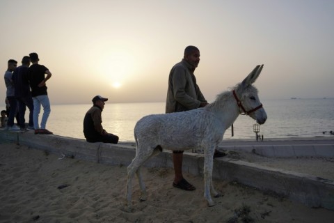 Palestinians watch as a ship transporting humanitarian aid sails in the water near the central Gaza Strip 