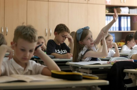 A first-grader raises her hand during a lesson at the 61st secondary school in Kyiv, on May 24, 2024