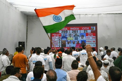 A supporter of the Indian National Congress (INC) party waves the national flag as others watch results during vote counting in New Delhi