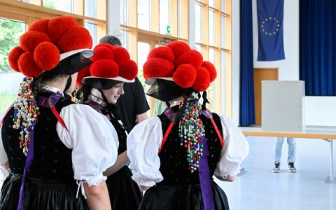 Women wearing 'Bollenhut' pompon hats typical of the Black Forest region line up to vote in Gutach, southern Germany