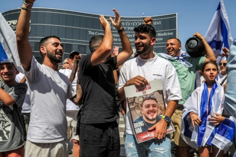 A man holds a picture of freed hostage Almog Meir Jan outside a hospital in central Israel