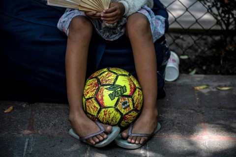 A girl waits with her family outside a migrant shelter in Mexico City