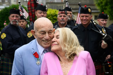 Newly-weds Jeanne Swerlin, 96, and US WWII veteran Harold Terens, 100, pose for photographs in front of a piper band in Normandy, northwestern France