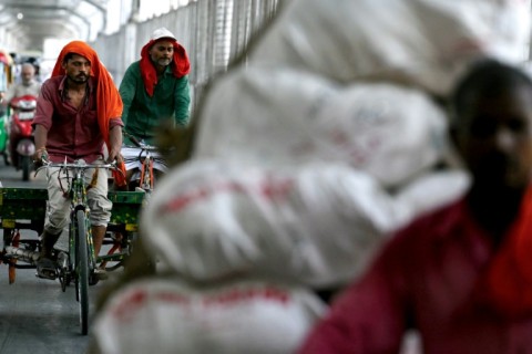 Men wearing scarves ride their carts on a hot summer day in New Delhi on June 18 