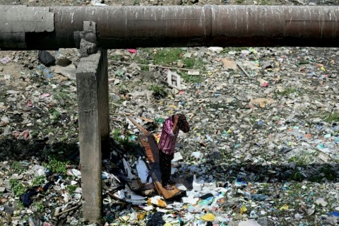 A man uses water dripping from a pipe to wash and cool on a hot summer day in New Delhi on June 18