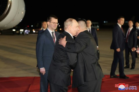 Russia's Vladimir Putin (L) and North Korea's Kim Jong Un embraced on the runway in Pyongyang early Wednesday