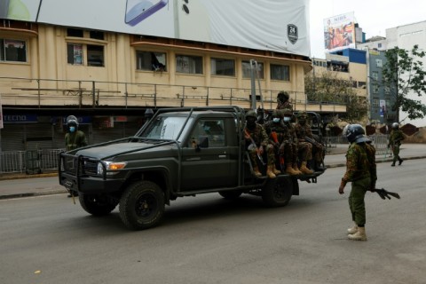 A patrol car from the Kenya Defence Forces drives past policemen during fresh demonstrations