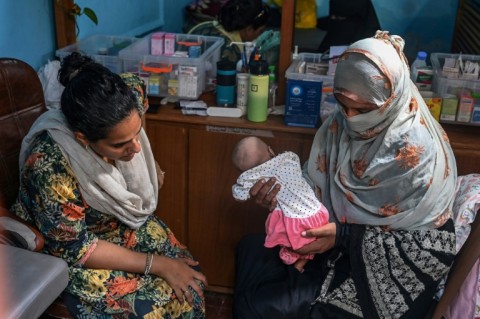 Midwife Neha Mankani (L) examines an infant at a clinic in Baba island, in Karachi