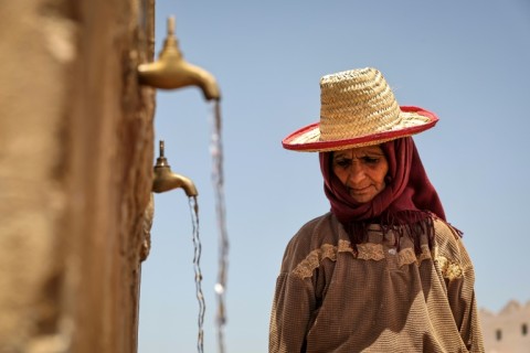 A Moroccan woman fills containers with scarce water in Sidi Slimane