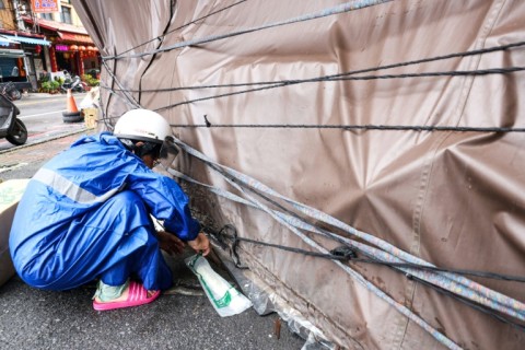 A shop owner tightens canvas around his booth to prevent possible damage as Typhoon Gaemi approaches in Yilan 