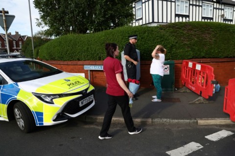 A woman arrives with a floral tribute to pay her respects at Hart Street in Southport, northwest England, on July 29, 2024, following a knife attack