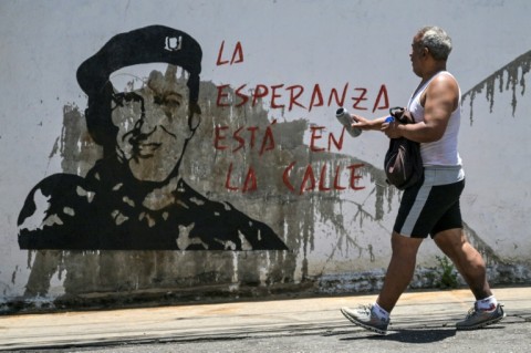 A man walks in front of graffiti showing former Venezuelan president Hugo Chavez in the Petare neighborhood in Caracas 