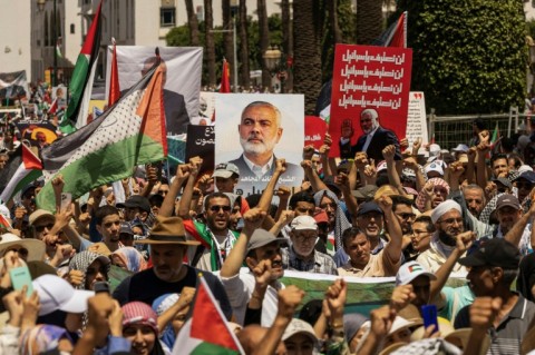 Demonstrators lift placards with Ismail Haniyeh's image and Palestinian flags during a rally in Rabat, Morocco