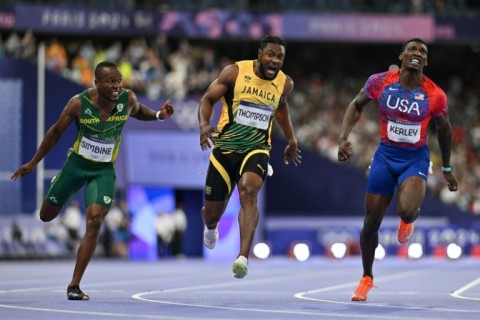 Jamaica's Kishane Thompson crosses the finish line next to South Africa's Akani Simbine and Fred Kerley of the USA