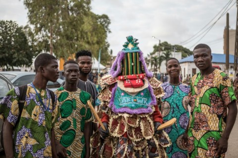 Paradegoers pose with an egungun, a traditional Yoruba figure, at the Porto Novo Mask Festival