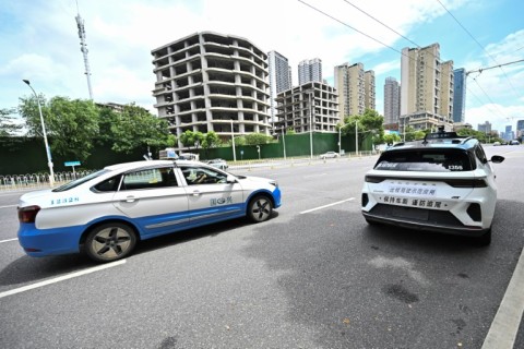 A regular taxi overtakes a driverless one in Wuhan, home to one of the world's largest robotaxi networks