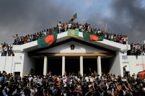 Protesters display Bangladesh's national flag as they storm Sheikh Hasina's palace