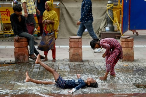 Children play after rainfall in the old quarters of Delhi on August 8