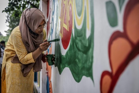 A student paints a wall with revolutionary slogans to cover old murals related to the regime of Sheikh Hasina and the Awami League party: the colourful new murals hint at widespread faith among Bangladeshis of a better future 