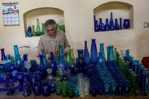 Ghulam Sakhi Saifi arranges glassware at his shop in Afghanistan's western city of Herat