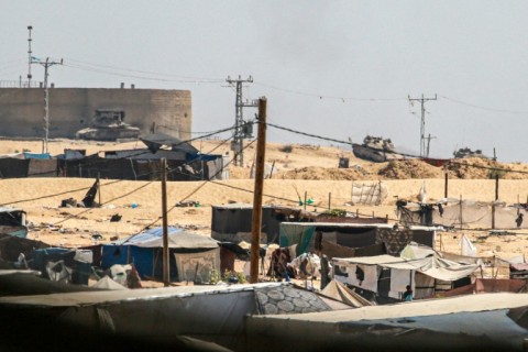 Israeli army tanks take position on a hill overlooking a makeshift displacement camp in the southern Gaza Strip